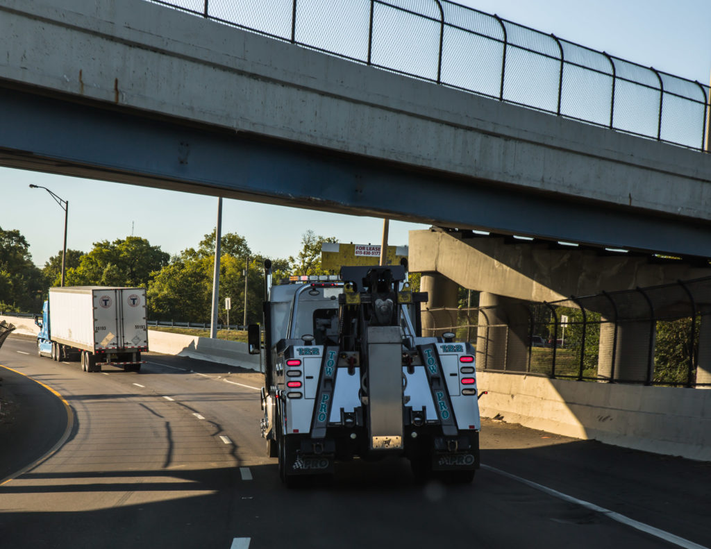 tow truck driving under an overpass on the highway