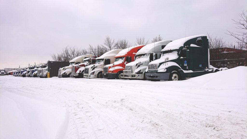fleet of semi trucks covered in snow