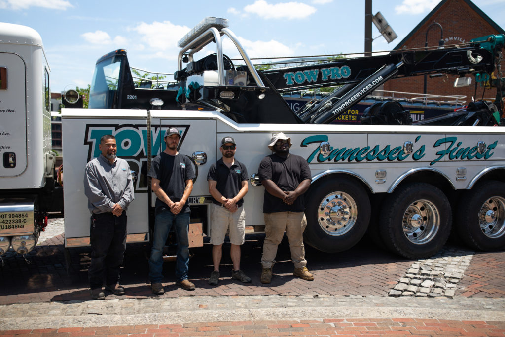 Tow Pro employees standing by tow truck