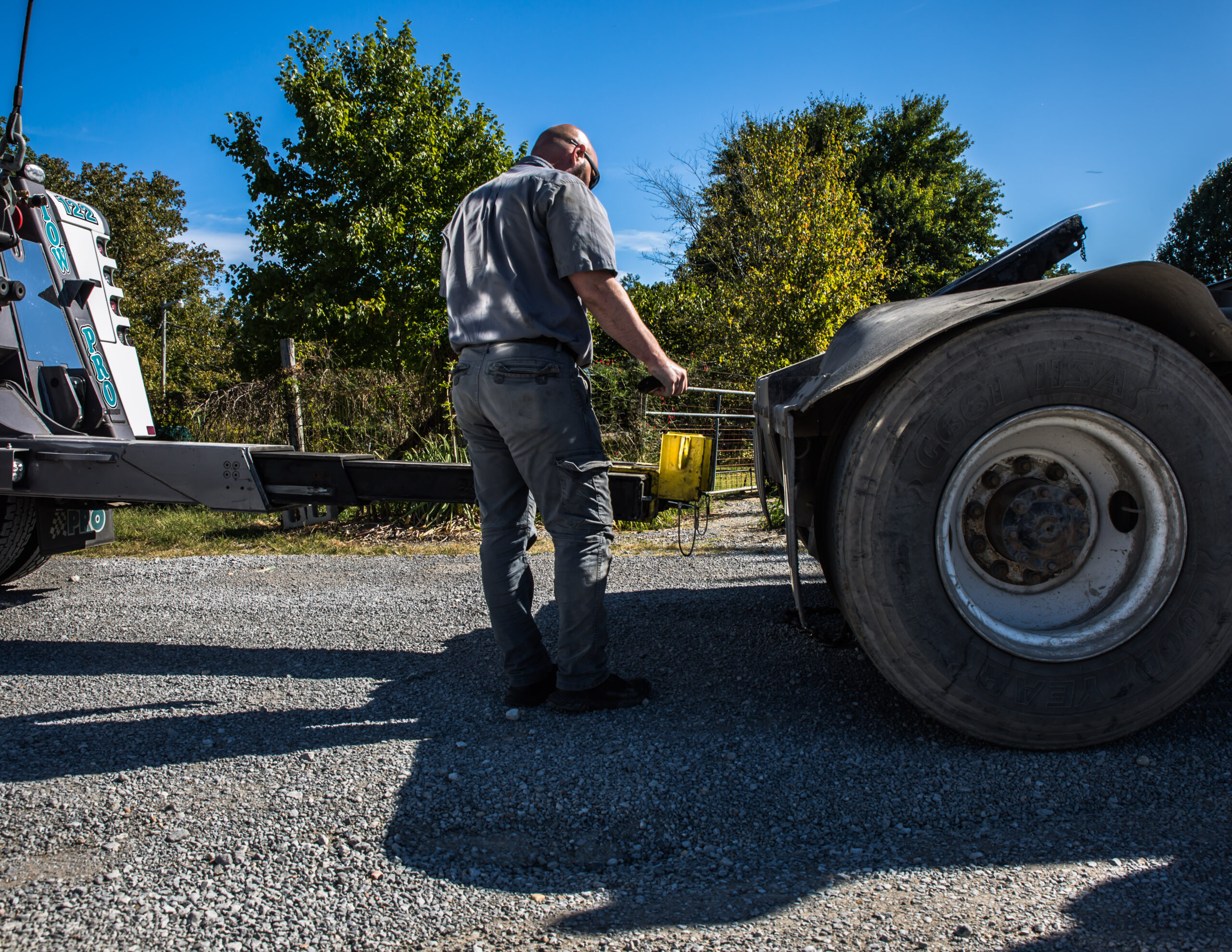 A tow pro truck driver on a clear sunny day, prepping a heavy duty vehicle to be ready for a tow.