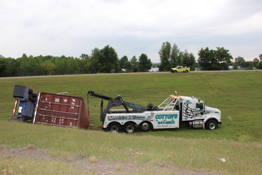 A Cotton's Towing truck lifting a sideways semi-truck.